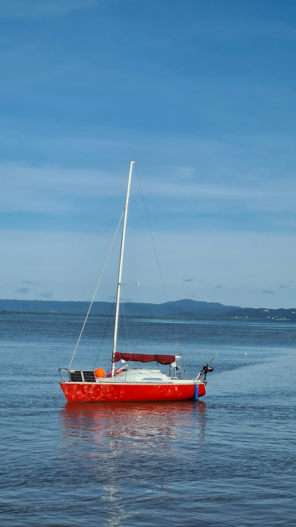 red and white boat on sea under white clouds during daytime