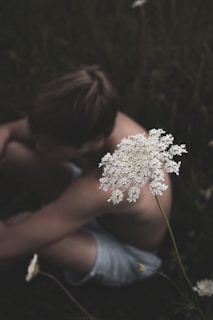 man in blue tank top holding white flower