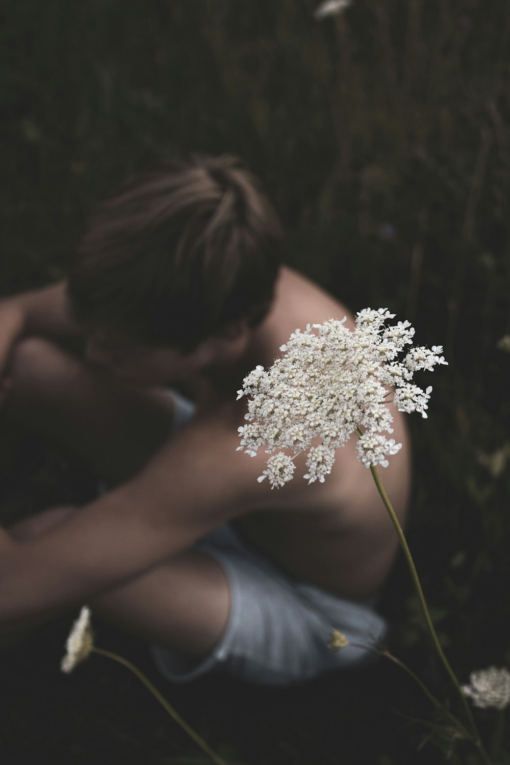 man in blue tank top holding white flower