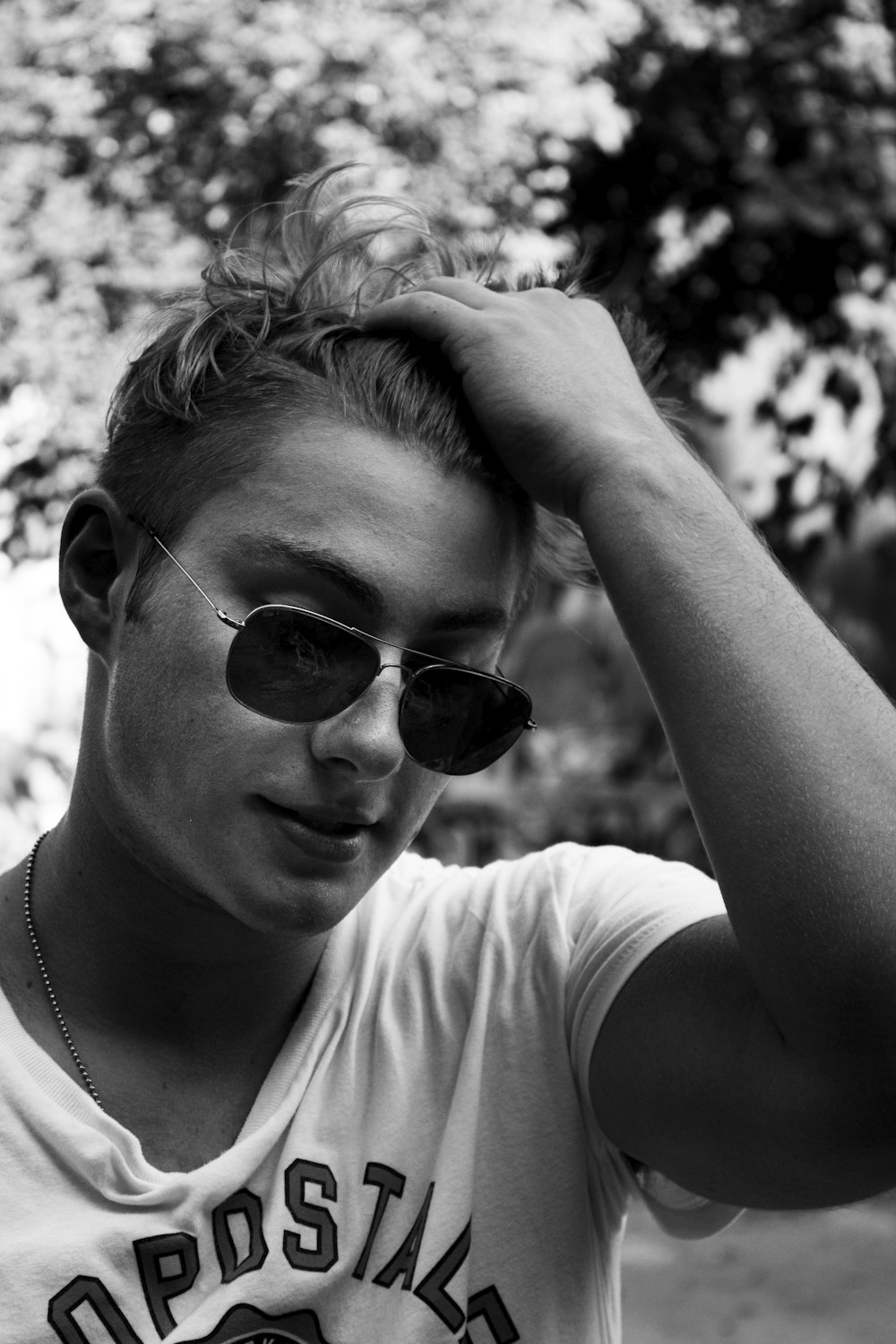 Photo en niveaux de gris d’un homme portant des lunettes de soleil et une chemise à col rond