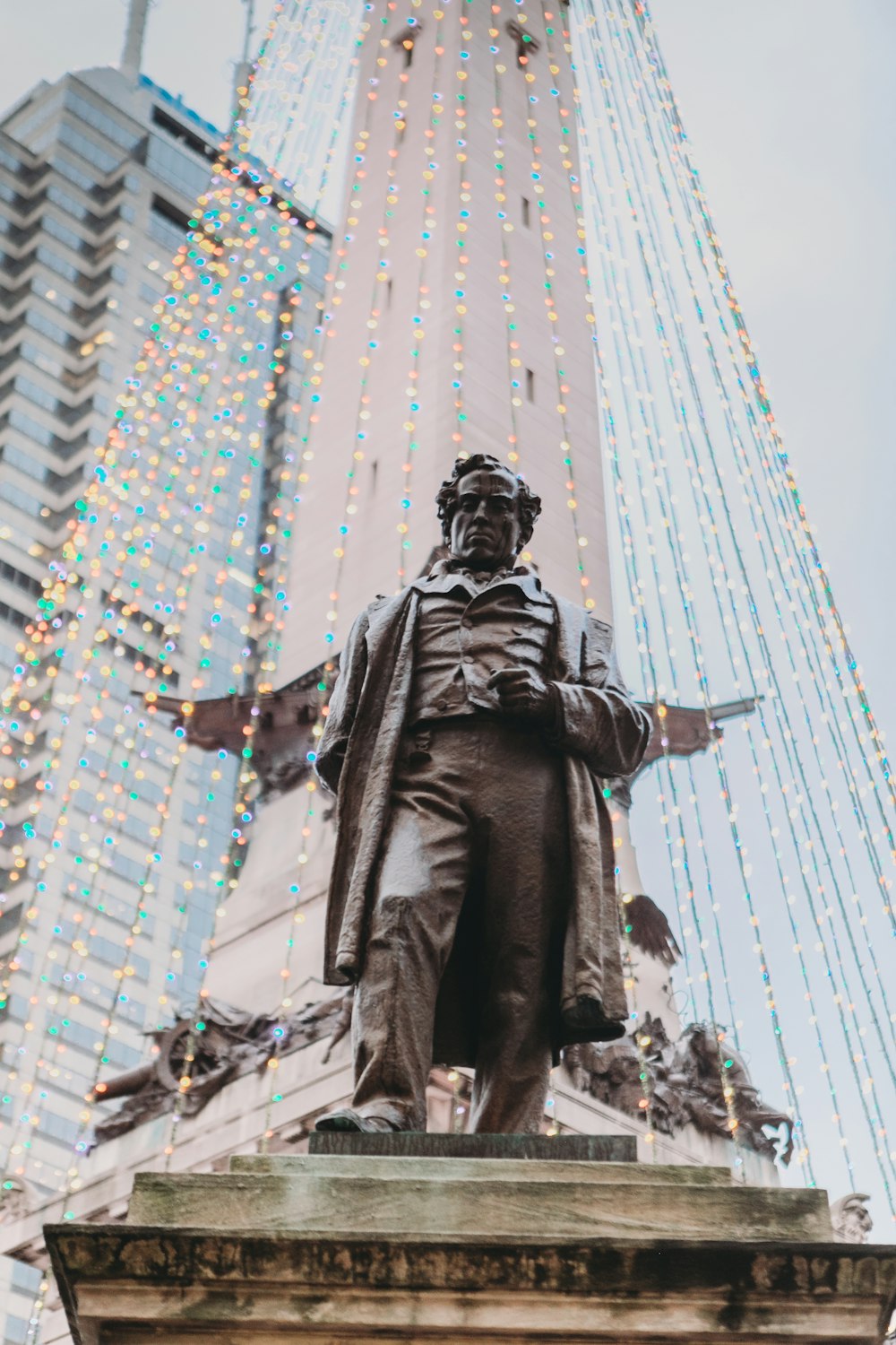 man statue near glass building during daytime