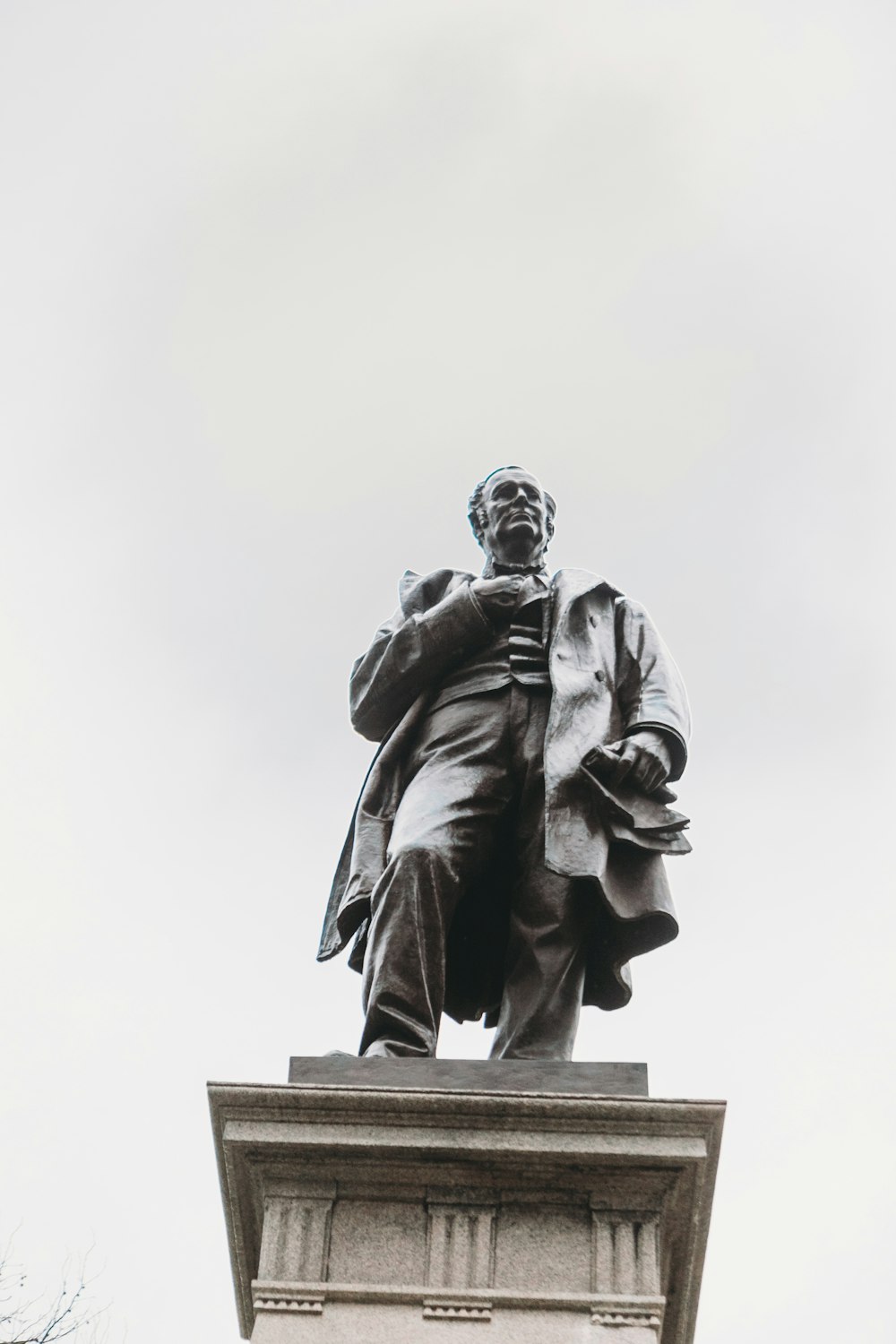 man in coat holding book statue