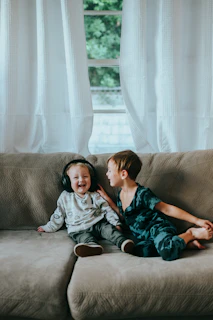 2 boys and girl sitting on brown couch