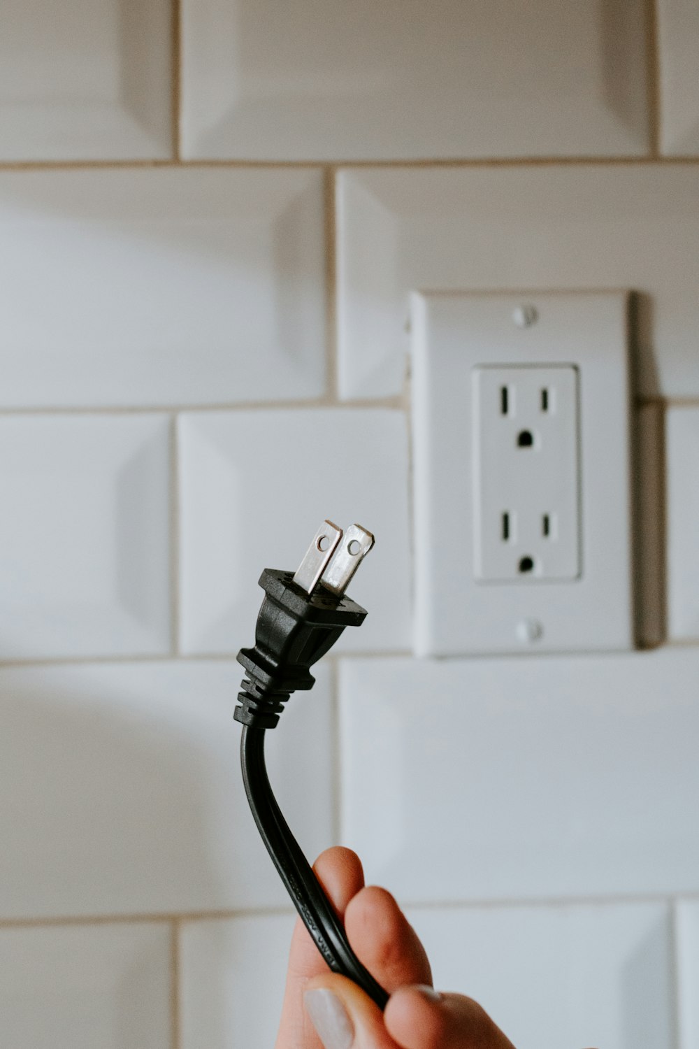 Cable USB negro enchufado en toma de corriente blanca