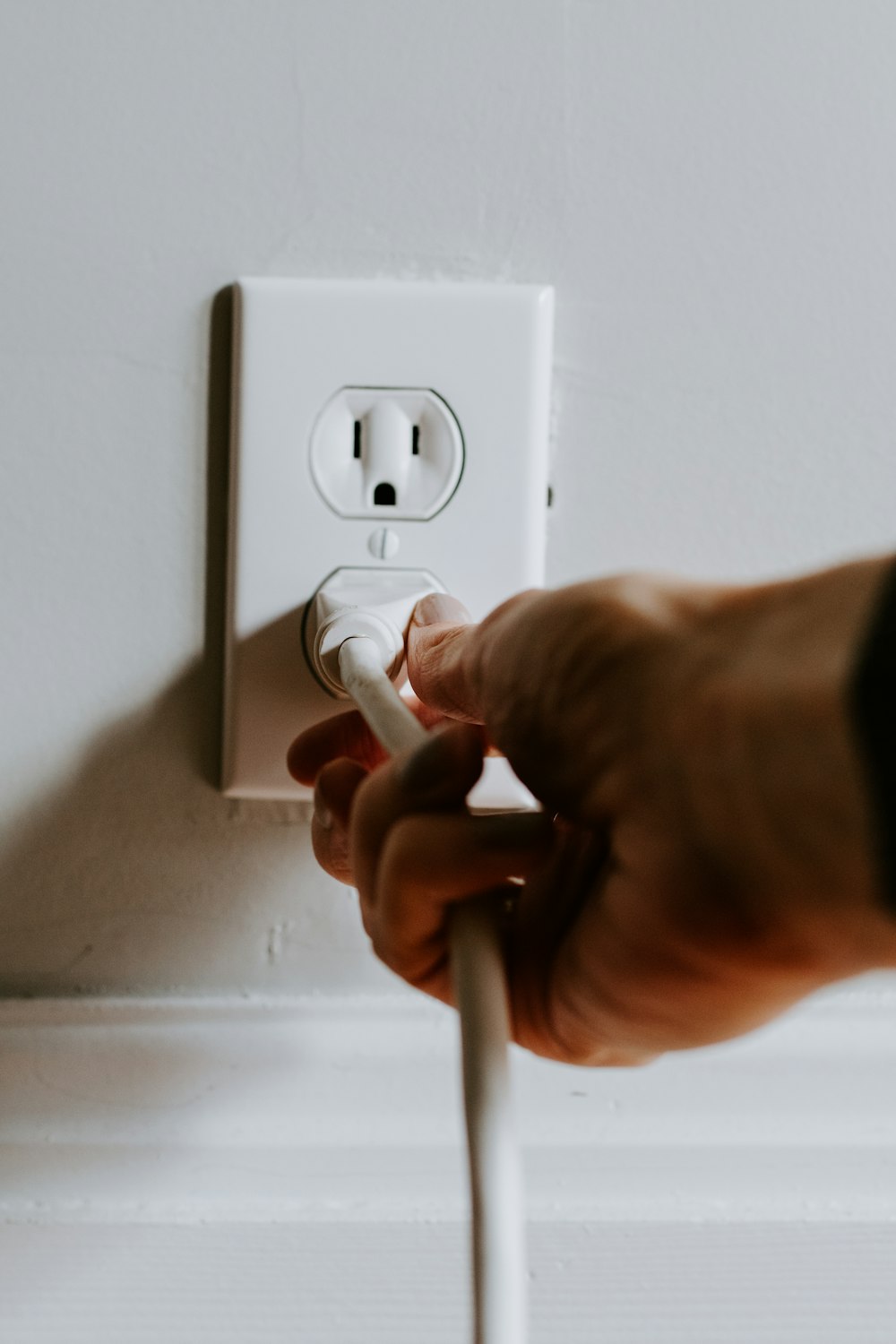 Persona sosteniendo un enchufe eléctrico blanco