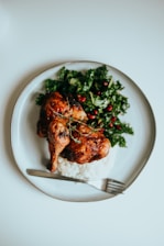 A colorful plate featuring roasted chicken with herbs and a side of fresh salad.