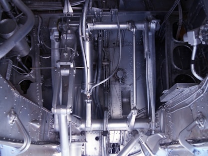A complex arrangement of mechanical parts and components, including metal rods, pipes, and various interconnected structures. The image displays an intricate assembly of machinery with a metallic sheen and various textures, indicative of industrial engineering.