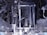 A complex arrangement of mechanical parts and components, including metal rods, pipes, and various interconnected structures. The image displays an intricate assembly of machinery with a metallic sheen and various textures, indicative of industrial engineering.