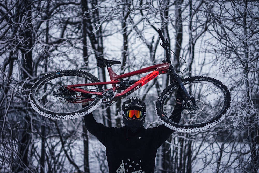 person in black jacket standing beside red and black mountain bike