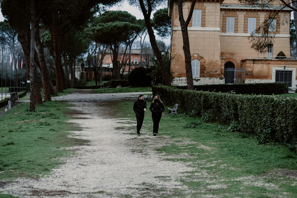 person in black jacket walking on gray concrete pathway during daytime