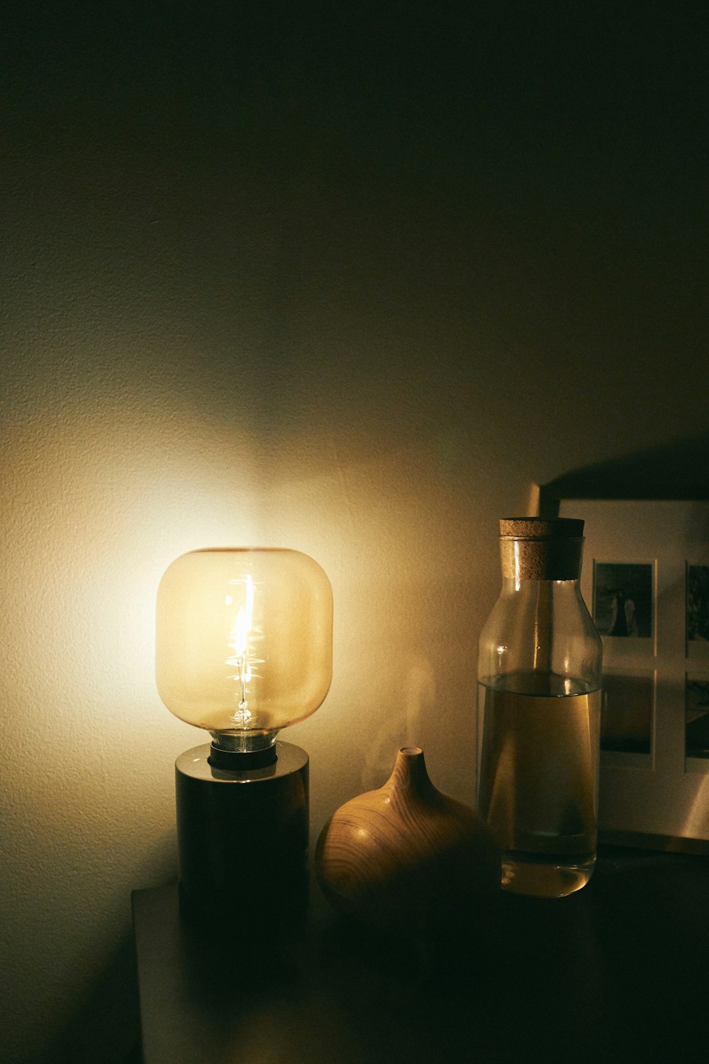 white table lamp turned on beside clear glass bottle