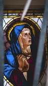 A serene stained-glass window depicting Saint Teresa in prayer.