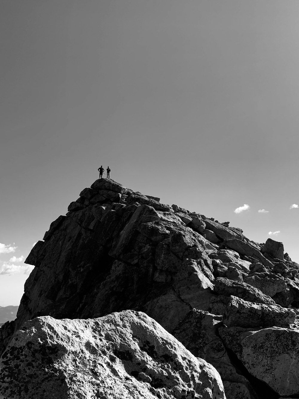 grayscale photo of person standing on rock formation