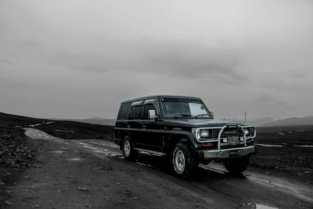 SUV nero su sabbia marrone sotto cielo nuvoloso bianco durante il giorno