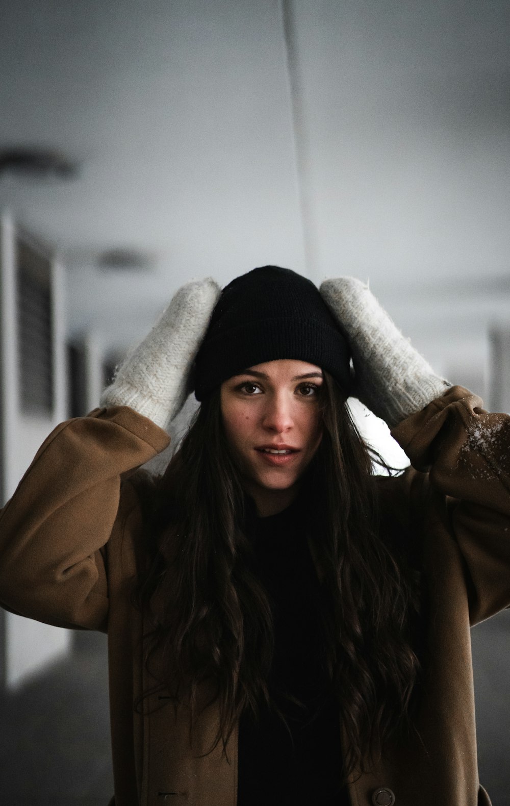 woman in brown coat wearing black knit cap