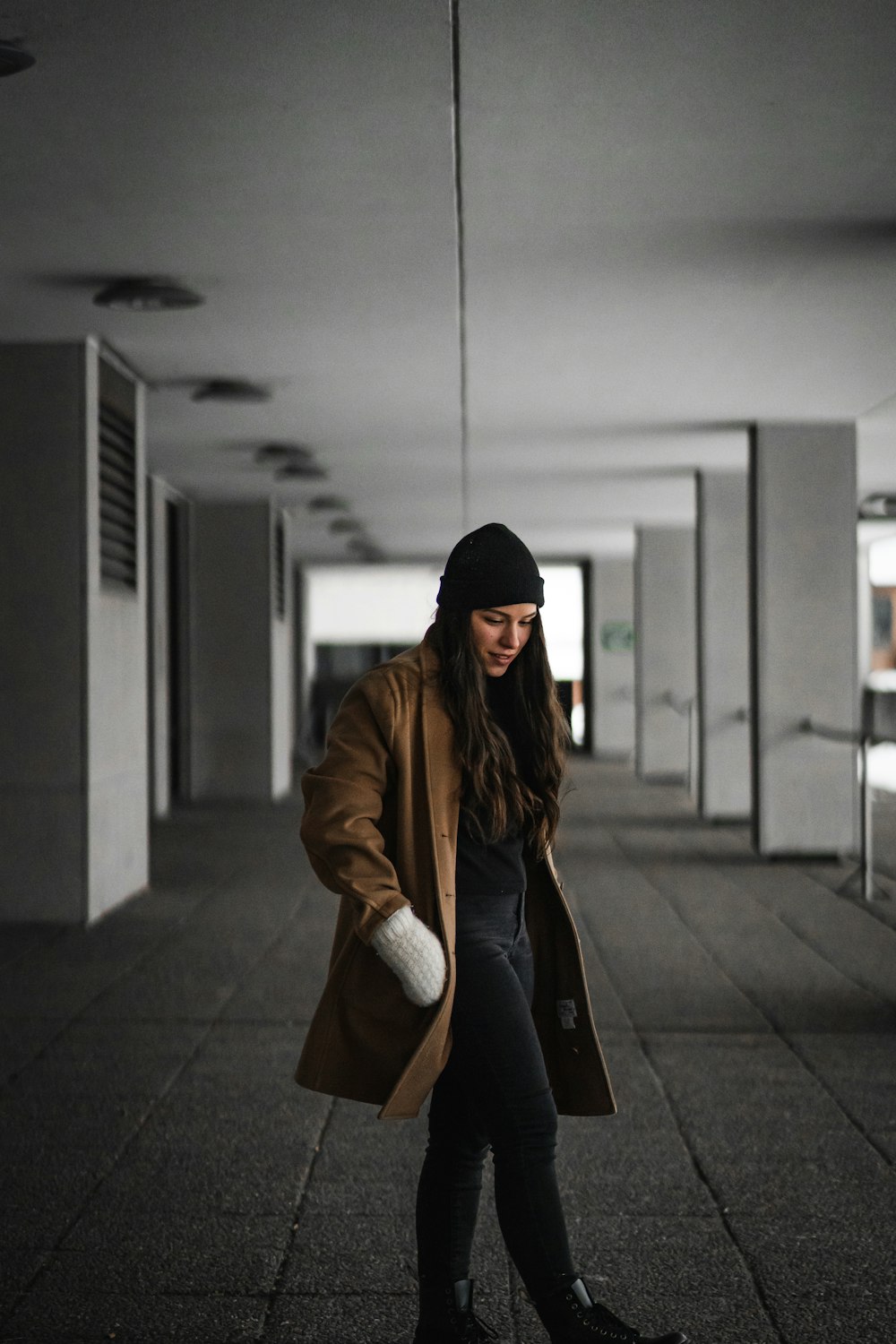 woman in brown jacket standing near gray wall