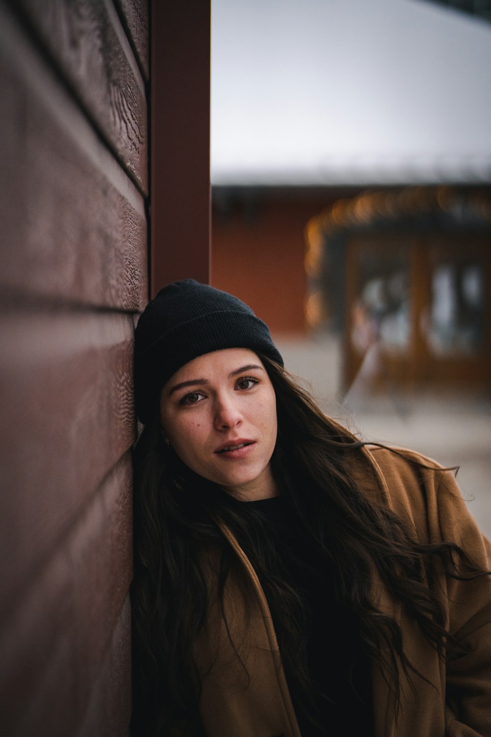 woman in black knit cap and brown jacket