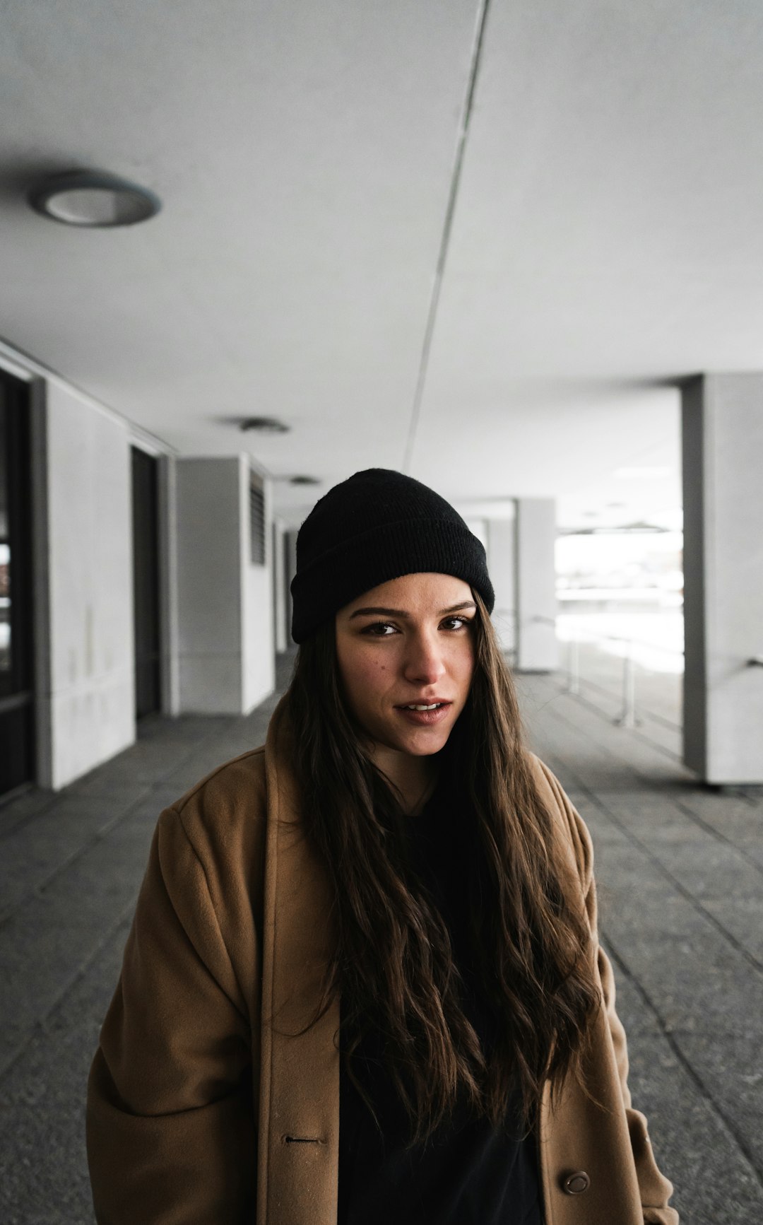 woman in black knit cap and brown coat