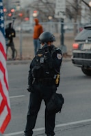 man in black and white uniform standing on road during daytime