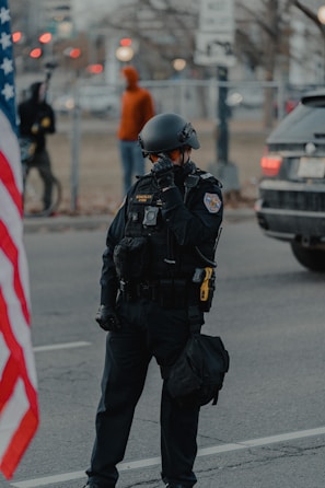 man in black and white uniform standing on road during daytime
