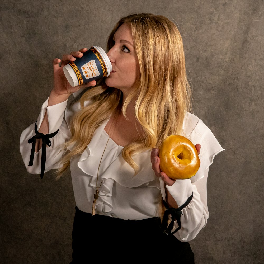 woman in white long sleeve shirt holding brown and white labeled can