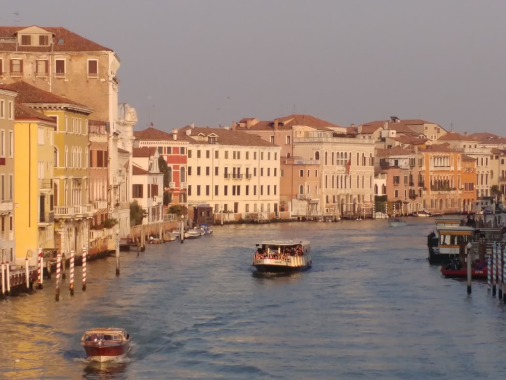 people riding on boat on river near buildings during daytime