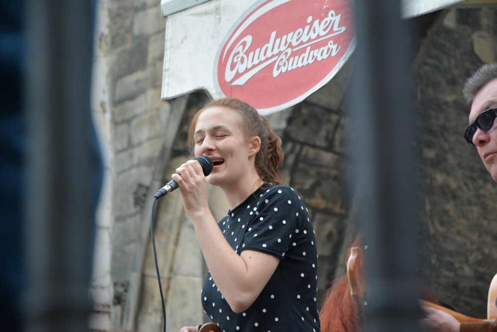 woman in black and white polka dot dress singing