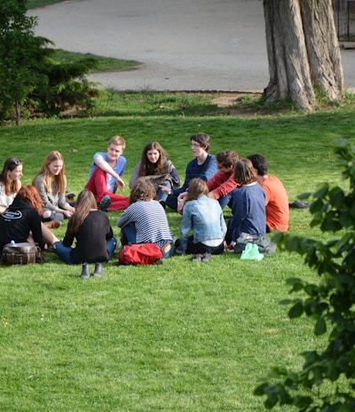 group of people sitting on green grass field during daytime