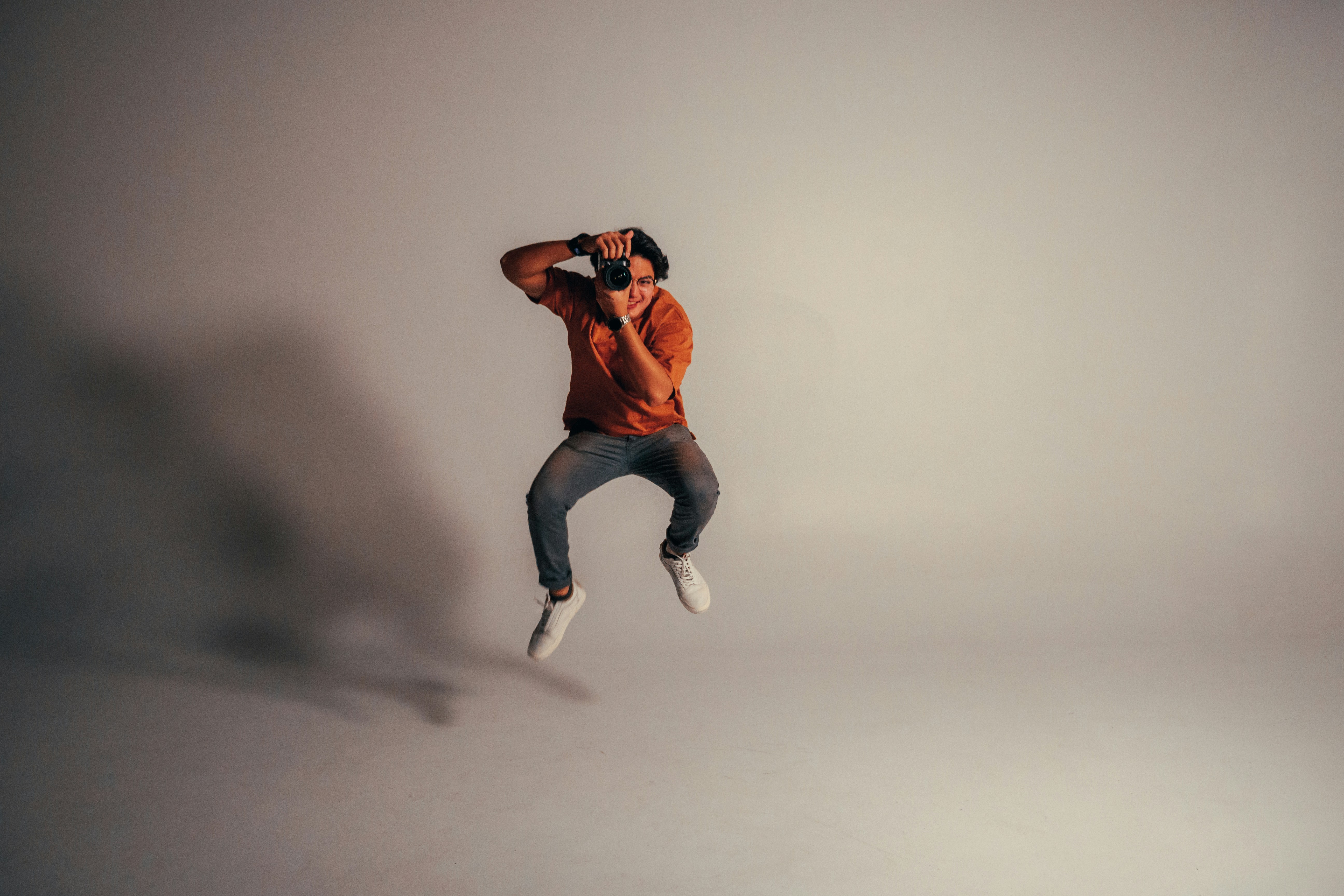 Man in orange t-shirt and blue jeans jumping