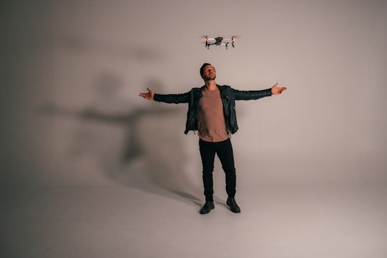 Warm portrait of a photographer holding a drone controller in a soft pastel-themed studio.