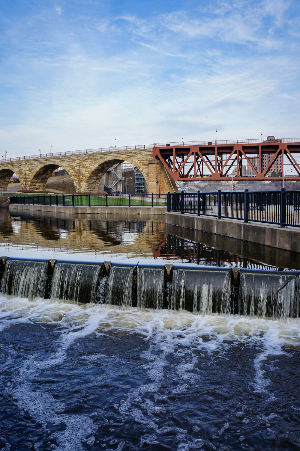 water falls under bridge during daytime