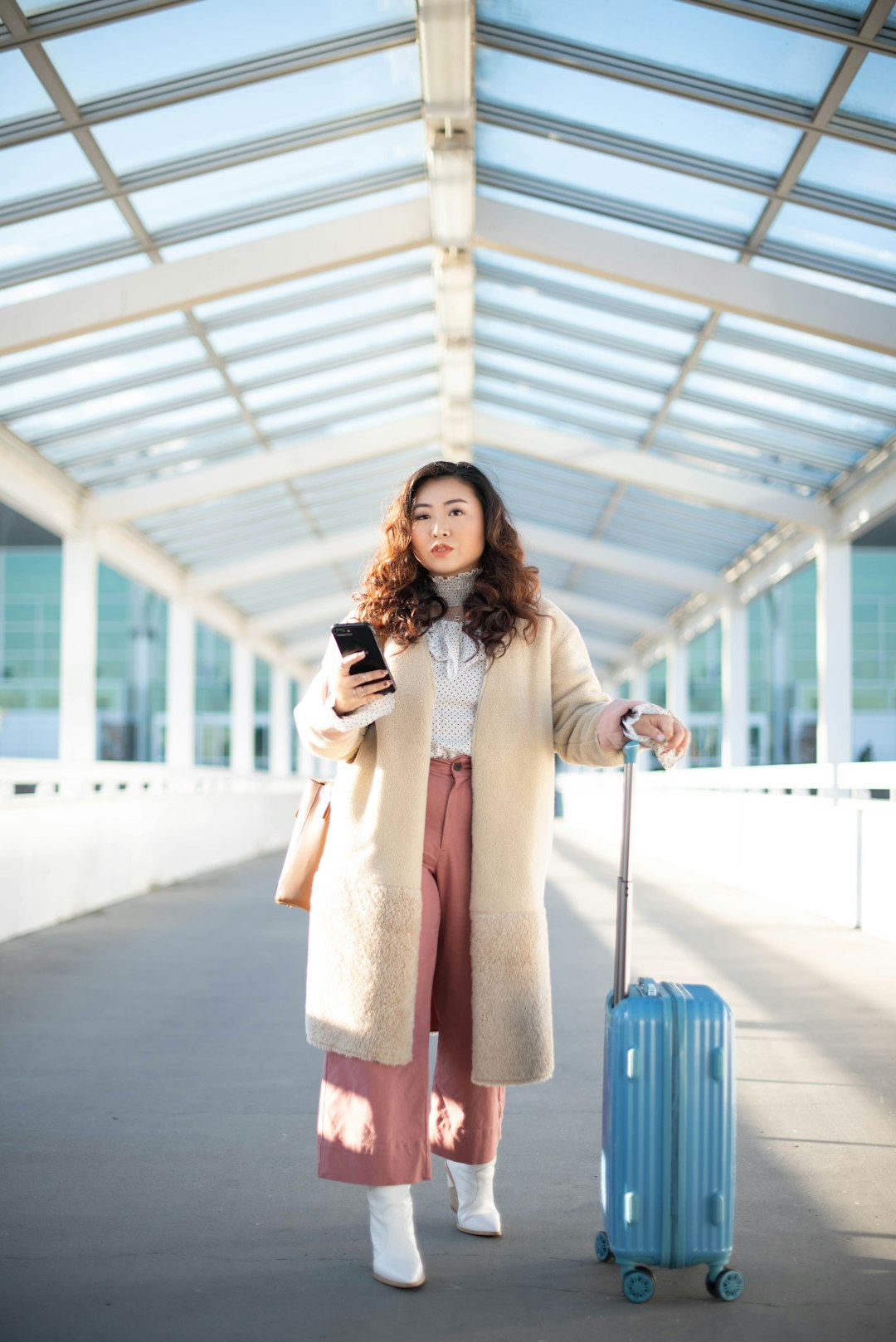 woman in beige long sleeve dress holding blue handbag