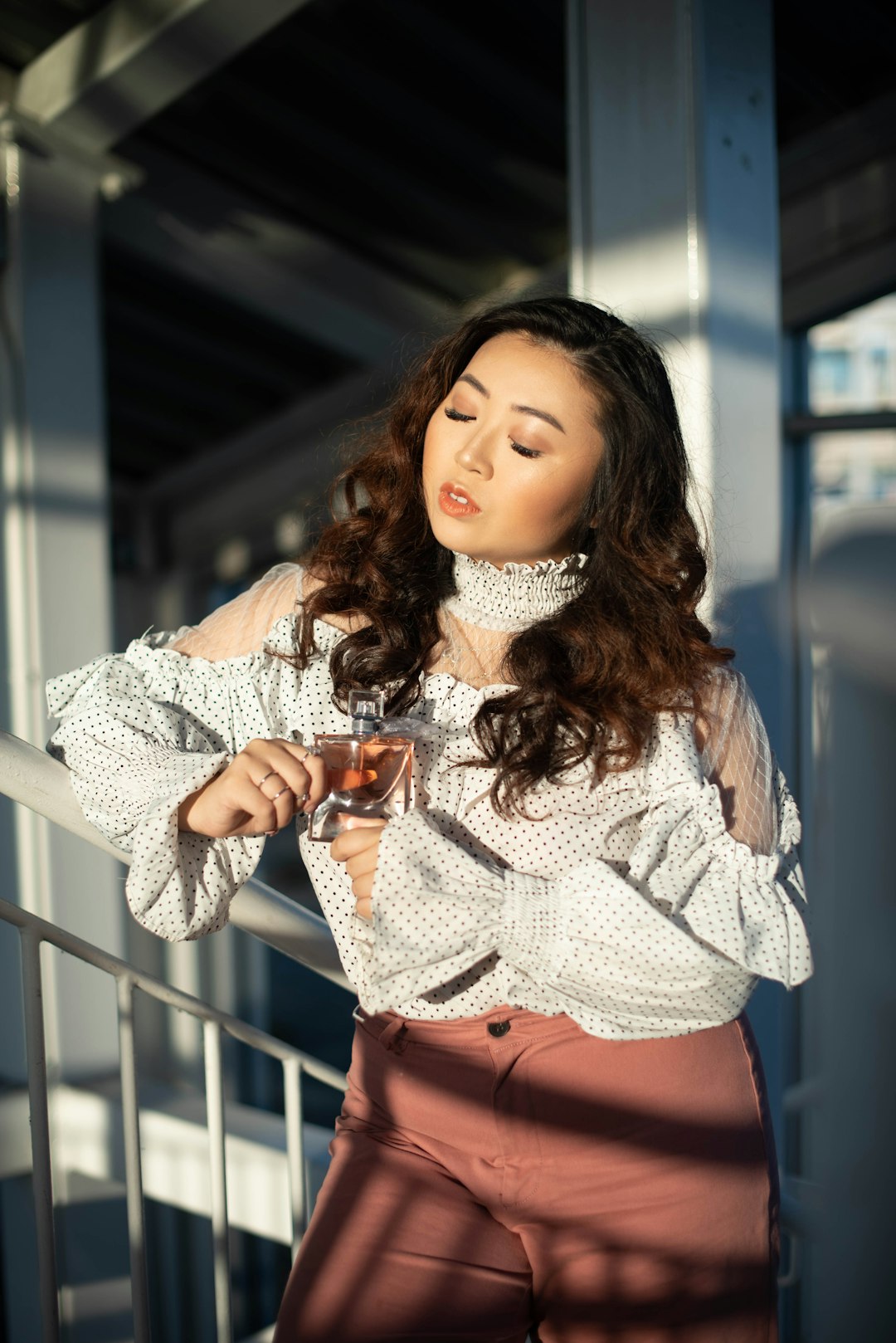 woman in white knit sweater and orange skirt holding clear drinking glass