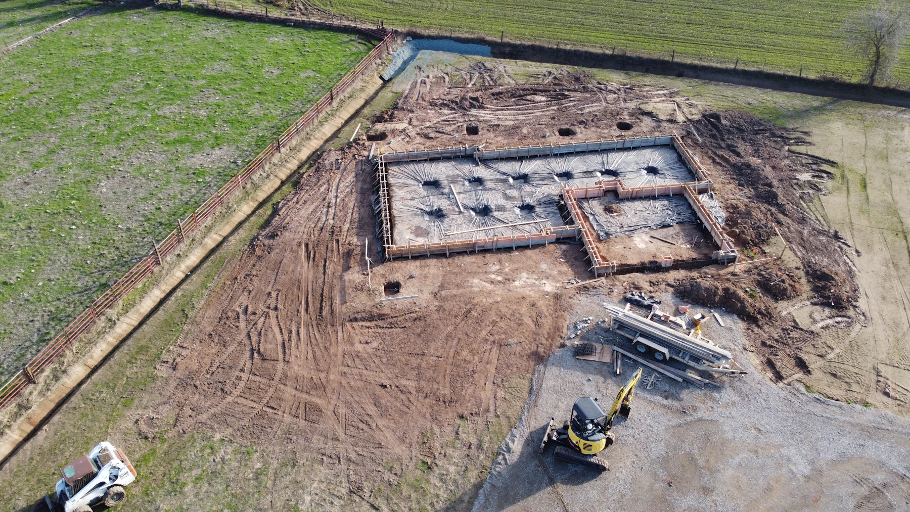 Drone view of foundation formwork with perimeter excavation and site drainage ditch