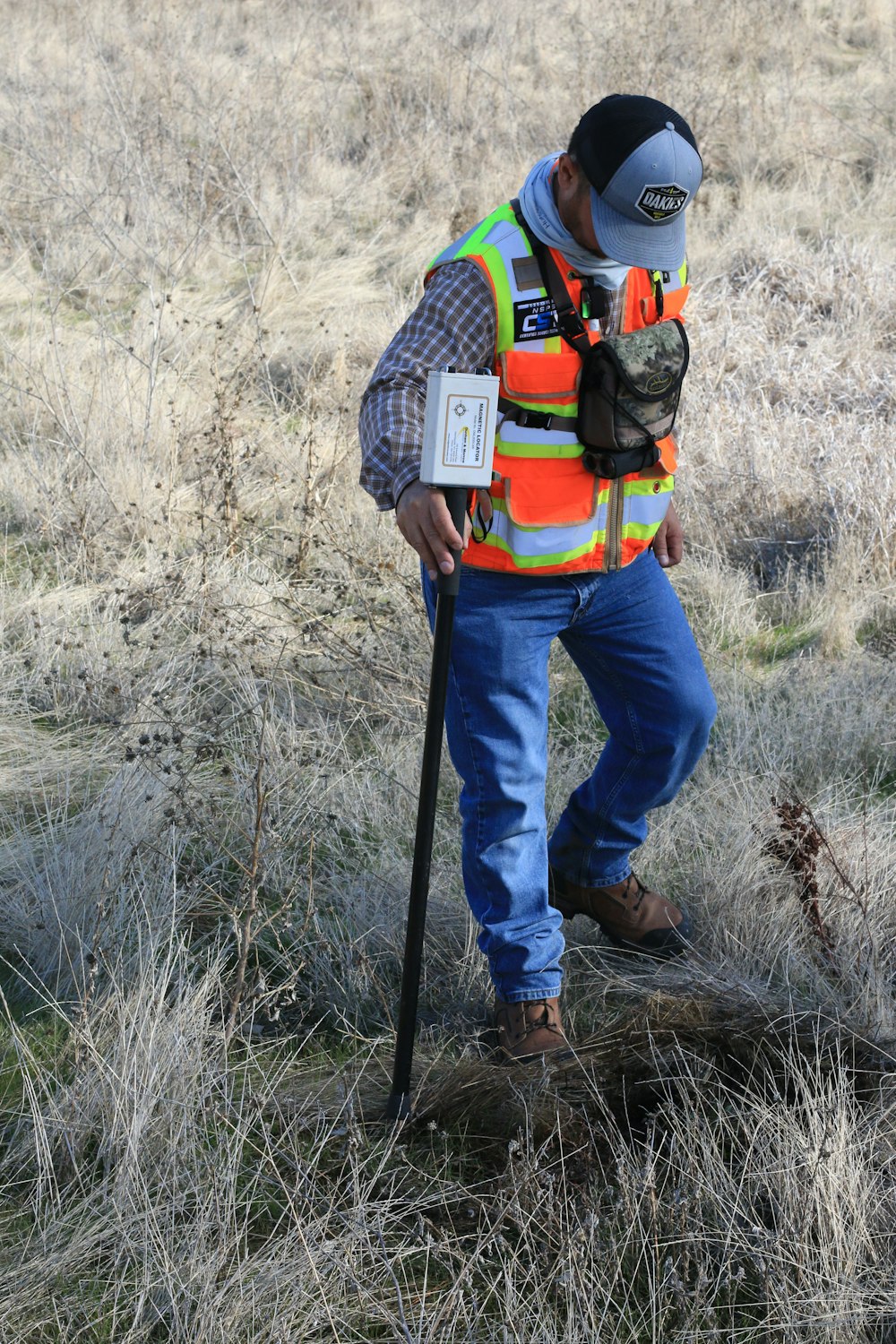 man in orange and black backpack and blue denim jeans standing on brown grass field during