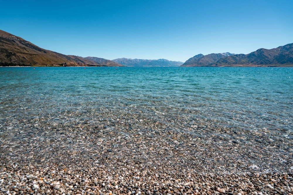 blue sea near brown mountain under blue sky during daytime