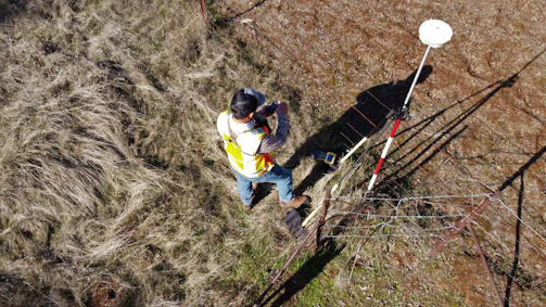 Surveyor marking land boundaries with stakes and measuring tools.