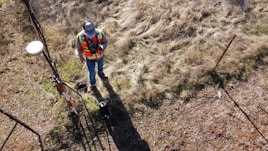 man in orange jacket and black helmet riding red bicycle on brown dirt road during daytime