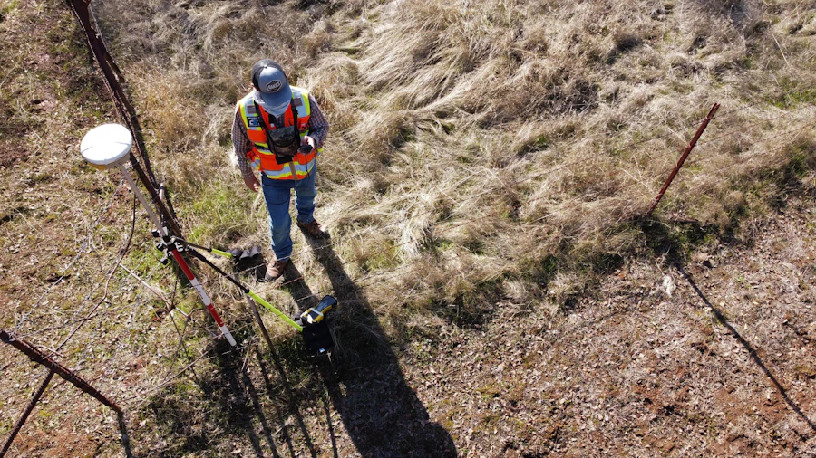 Topógrafo com equipamento GPS/GNSS em levantamento de campo, vista aérea