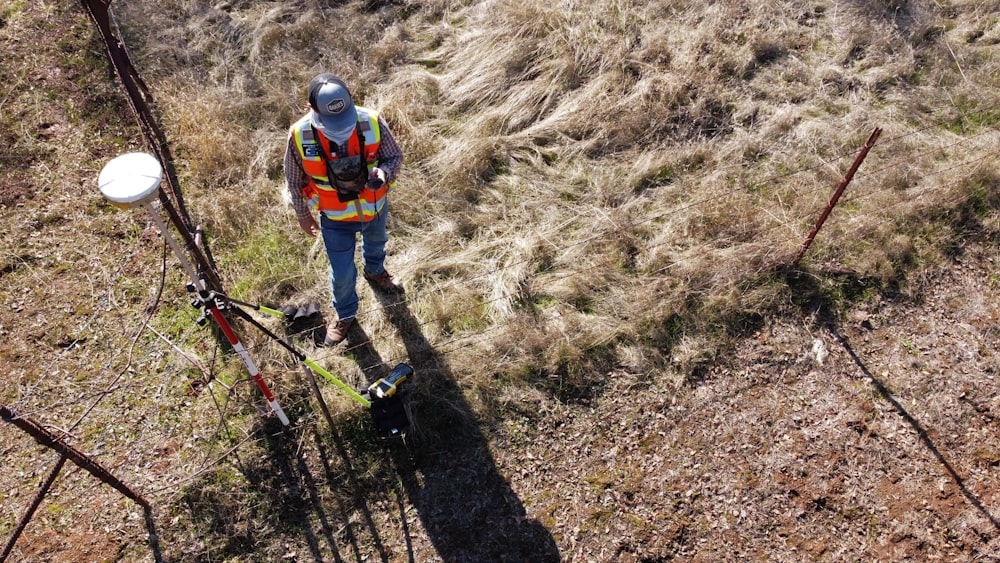 man in orange jacket and black helmet riding red bicycle on brown dirt road during daytime