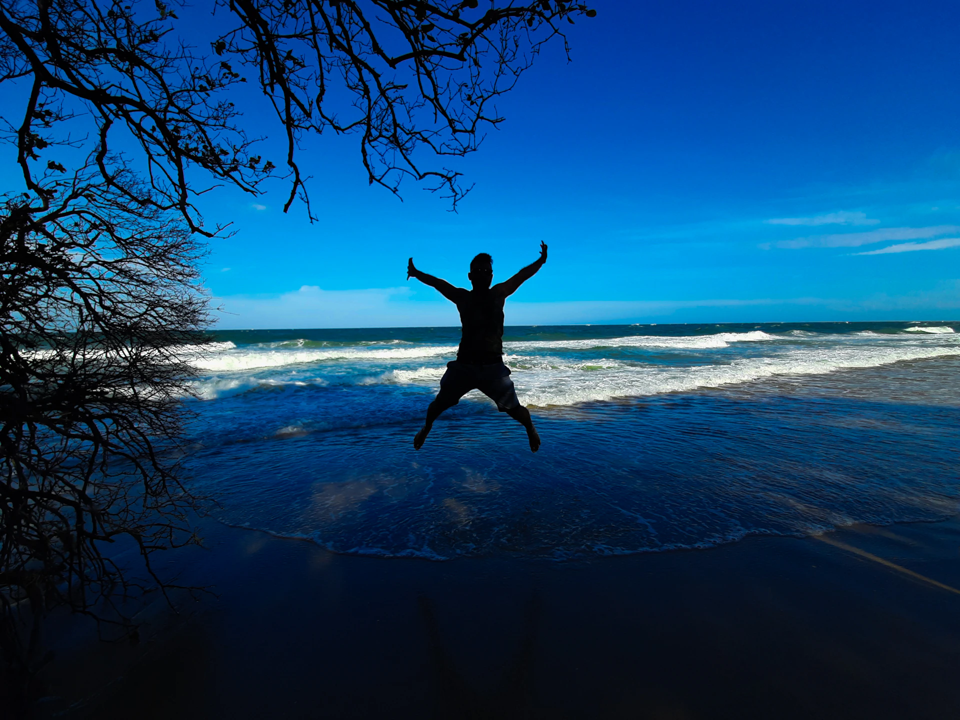 man jumping on the beach during daytime