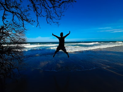 man jumping on the beach during daytime award-winning google meet background