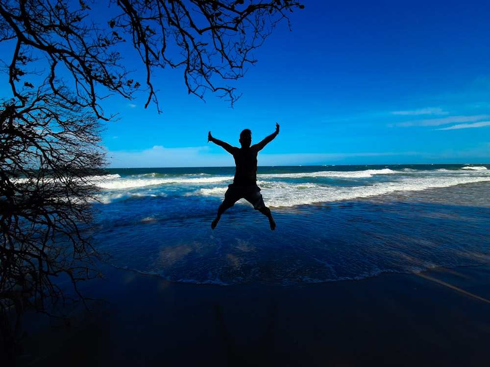 man jumping on the beach during daytime