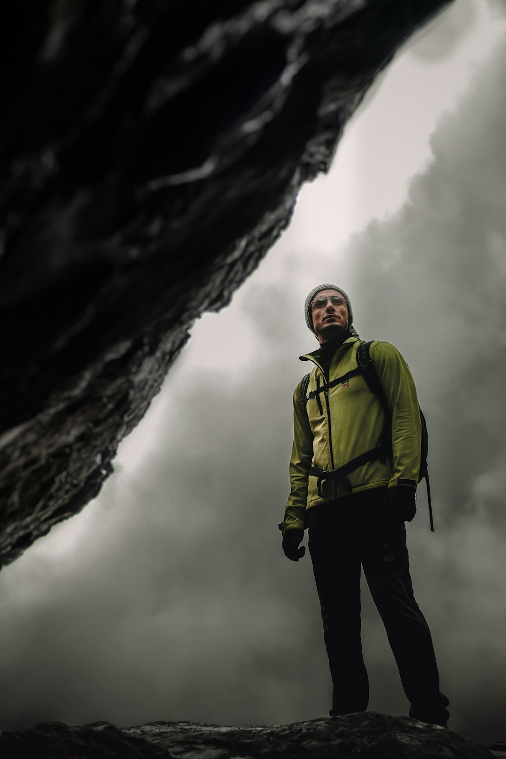 man in green jacket standing near rock formation