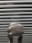 A close-up view of a compact fluorescent light bulb with a spiral shape set against a background of horizontal blinds.