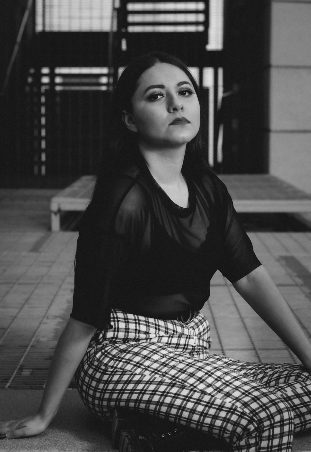 woman in black shirt and white and black plaid skirt sitting on floor
