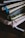 A stack of notebooks or journals with different colored covers and ribbon bookmarks is piled on a dark surface. The covers are textured, varying in patterns and colors, and the pages appear to be slightly used, suggesting regular use.