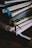 A stack of notebooks or journals with different colored covers and ribbon bookmarks is piled on a dark surface. The covers are textured, varying in patterns and colors, and the pages appear to be slightly used, suggesting regular use.