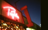 Close-up of a vibrant illuminated sign on a storefront at dusk.