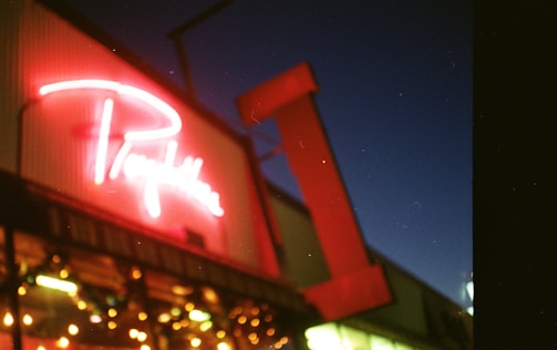Close-up of a vibrant illuminated sign on a storefront at dusk.